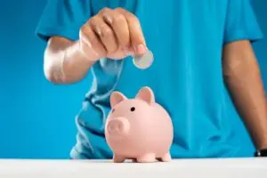 A man is putting a coin into a piggy bank.