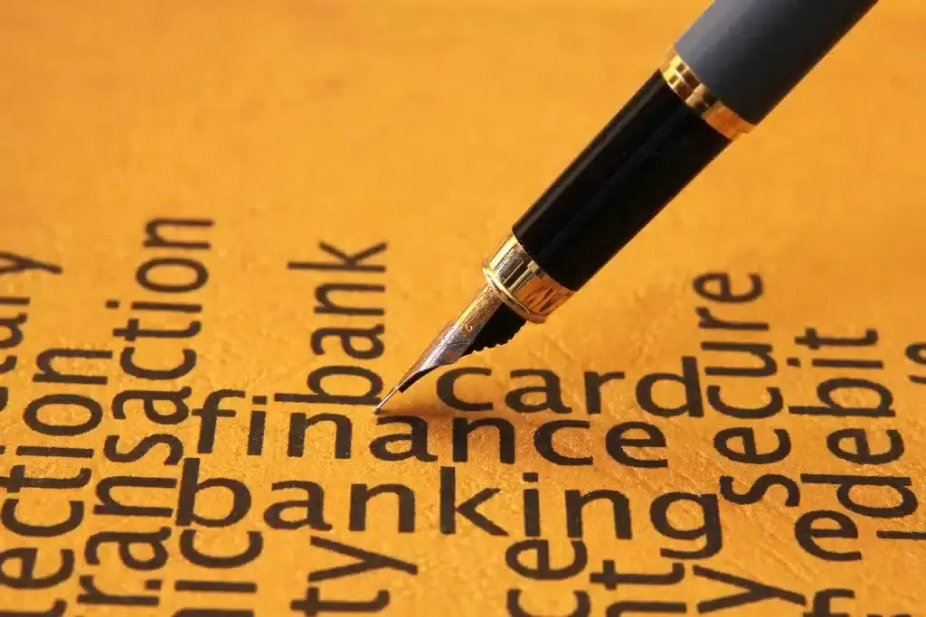 A pen is writing on a piece of paper with the words credit card finance banking.