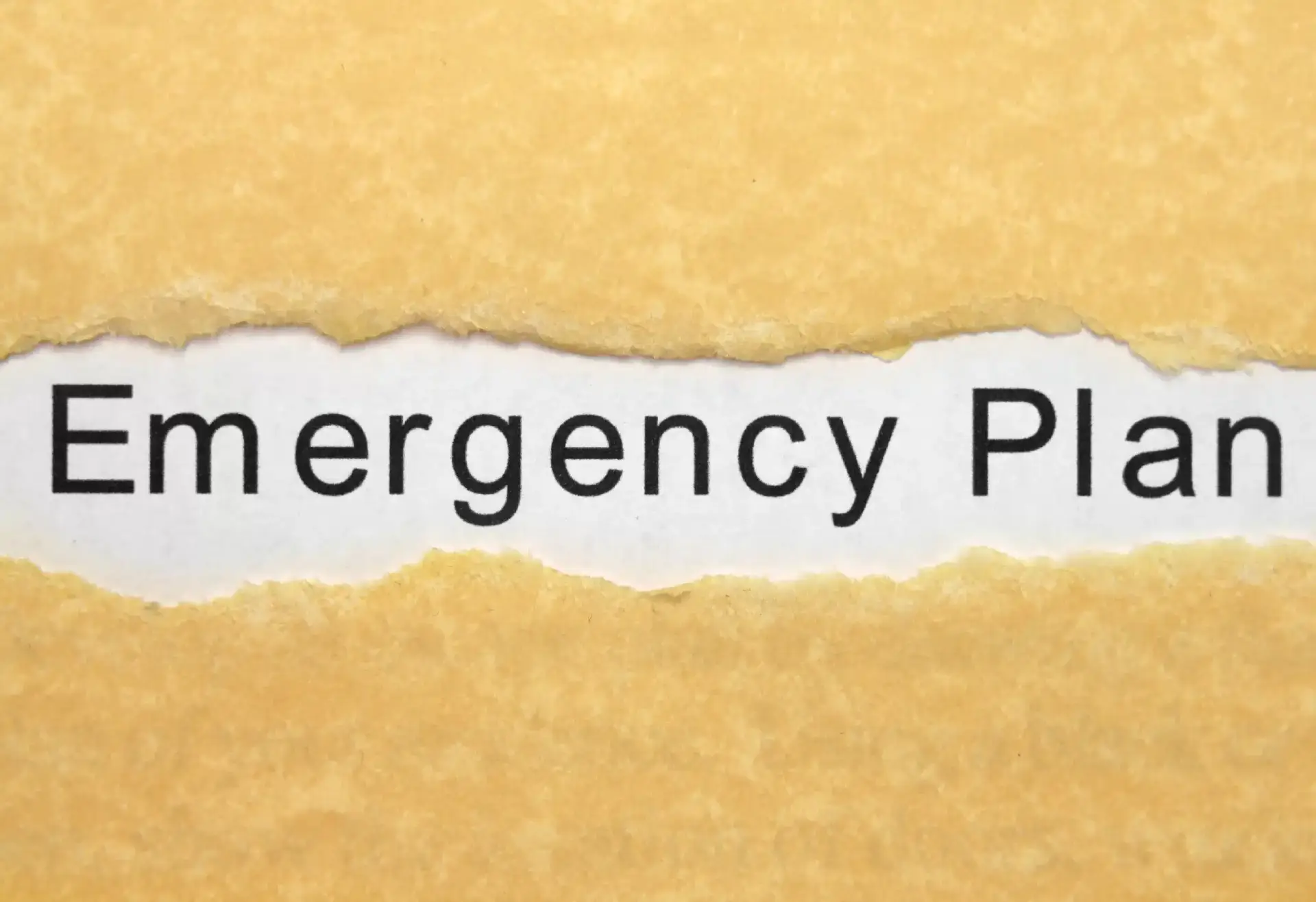 A ripped piece of paper with the word emergency plan, serving as a reminder for creating a solid financial security with an emergency fund