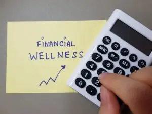 Person holding a calculator next to a yellow sticky note with "financial well-being" explained on it and a growth chart doodle.