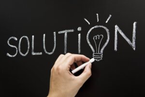 Hand drawing the word "solution" on a chalkboard, with a lightbulb cleverly replacing the letter "O", symbolizing how innovative ideas in 2025 will solve problems and pave the path to make money creatively.