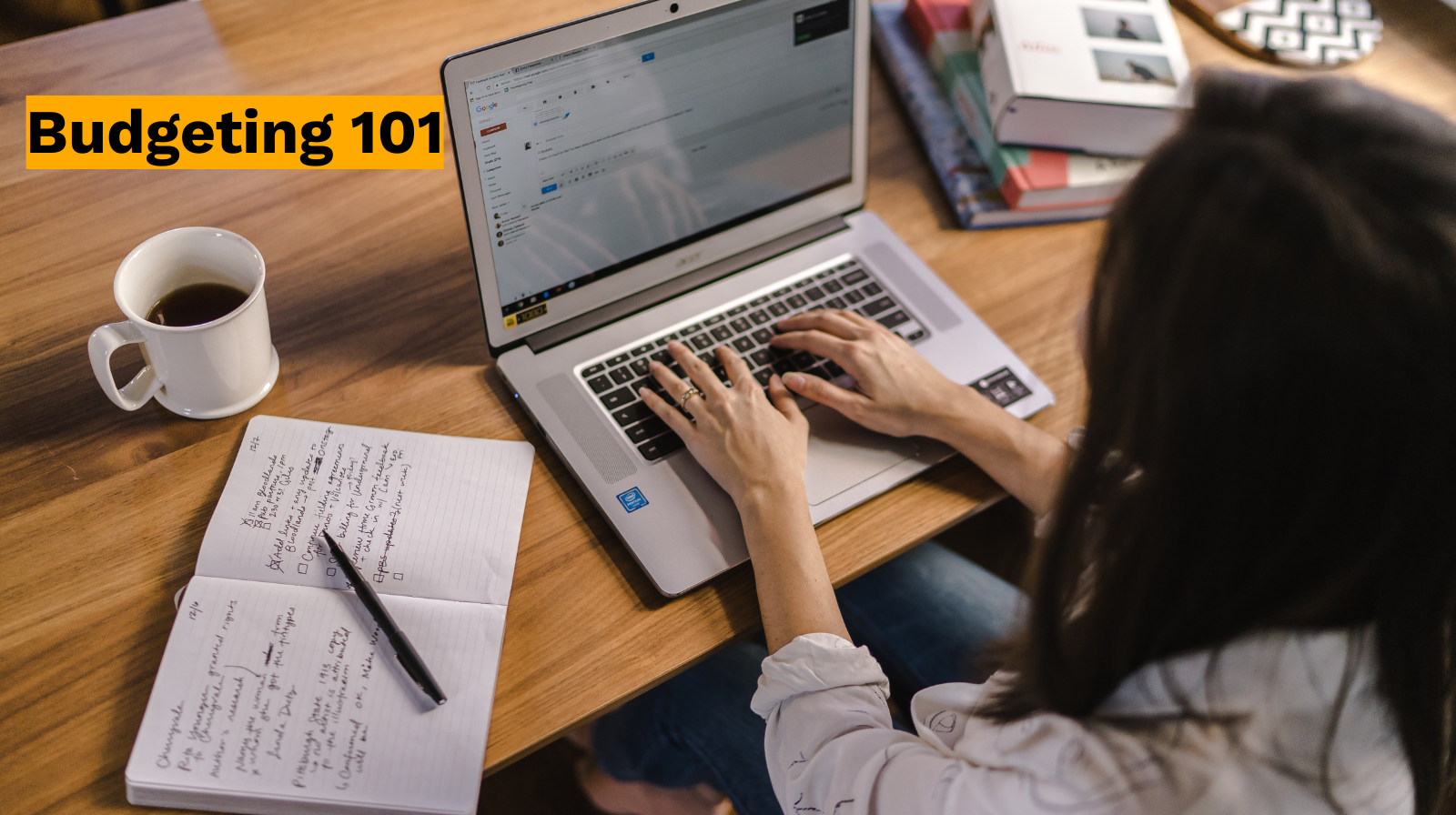 A person types on a laptop at a table with a notebook, pen, coffee cup, and books; "Budgeting 101" text in the top left hints at the first steps to wealth building.