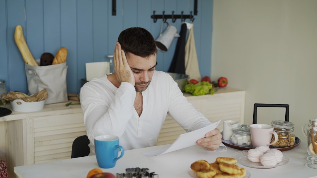 Paycheck to Paycheck: How to Stop the Cycle for Good 1 Man reviewing bills at the kitchen table while living paycheck to paycheck